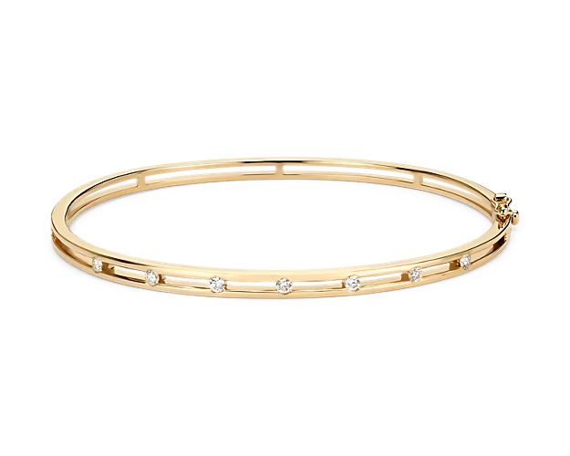 Delicately set in 14k yellow gold, this bangle has seven stationed diamonds for a little touch of elegance. The diameter of this bangle is 2 1/3" x 2".