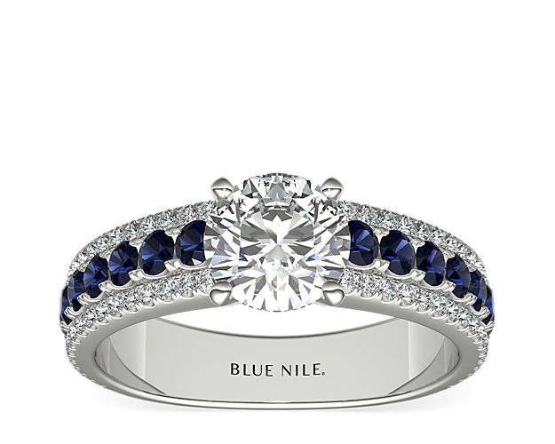 A row of boldly hued sapphires, flanked by dazzling pavé diamonds, provide a dazzling complement to the brilliant center stone of your choice in this gorgeous 14k white gold engagement ring.