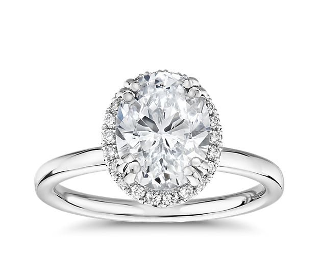 This Blue Nile Studio engagement ring combines the elegant simplicity of the platinum plain shank band with the stunning brilliance of an oval-shaped center stone encompassed in a halo of pavé-set diamonds.