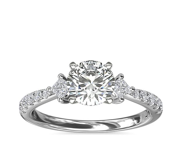 Go for a touch of whimsy with a beautiful design set in 14k white gold. This stunning style features two east-west princess-cut diamond sidestones and 10 round pavé-set diamonds flanking the center stone of your choice.