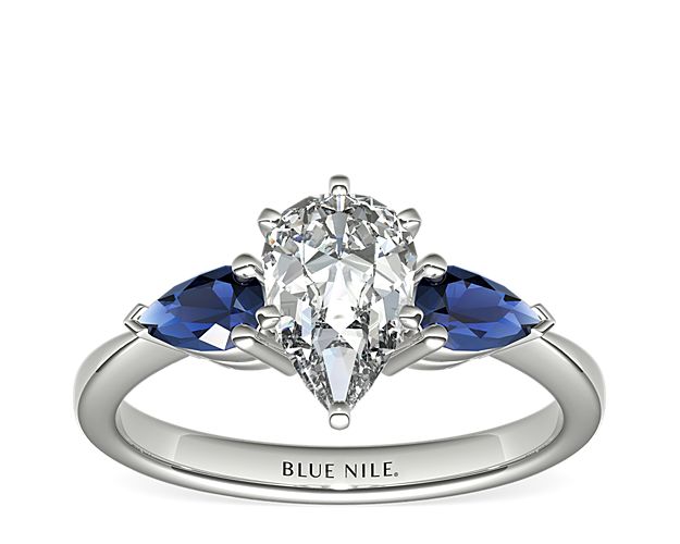 Two velvety medium dark blue pear-shaped sapphires, set in elegant platinum, draw the eye directly to the center diamond of your choice, making it the star of the show.